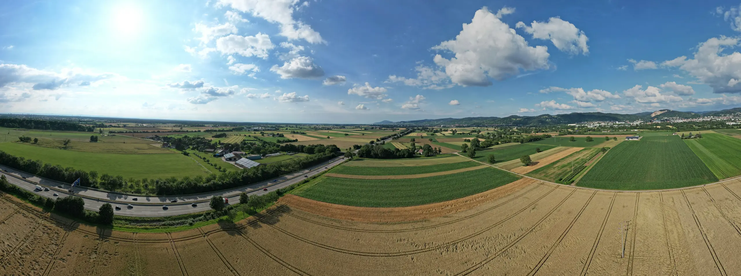 Aerial view of farmland divided into parcels, crossed by a highway